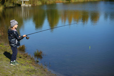 Rear view of man standing by lake