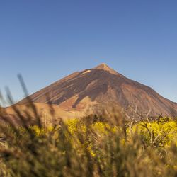 Scenic view of arid landscape against clear blue sky