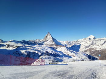 Scenic view of snowcapped mountains against clear blue sky