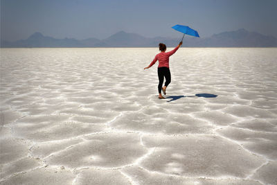 Rear view of woman with umbrella on beach