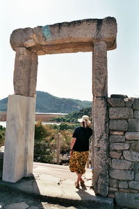 Rear view of woman standing by old castle against sky