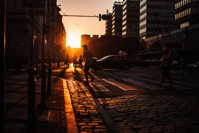 People crossing the street at sunset