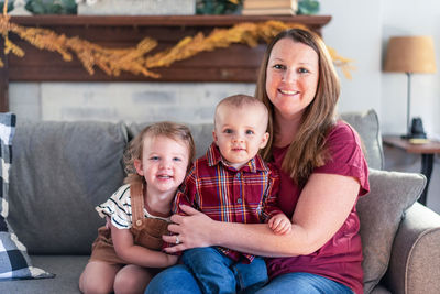 Portrait of mother with cute children sitting on sofa at home