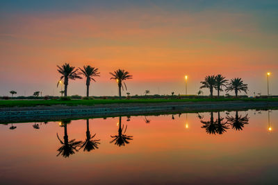 Scenic view of palm trees against romantic sky at sunset