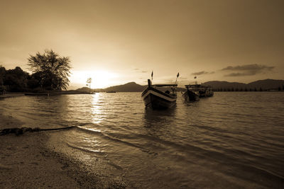 Boats moored in lake against sky during sunset