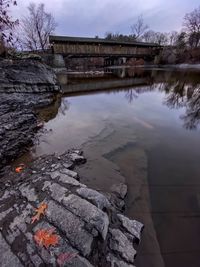 Bridge over lake by buildings against sky