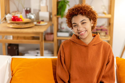 Portrait of young woman sitting on bed at home