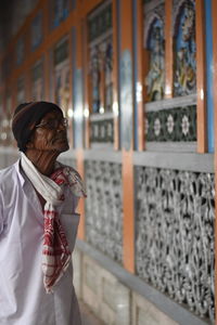 Woman looking away while standing against wall