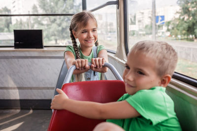 Kids ride in empty tram and look at the window with interest, public transportation, city tramway