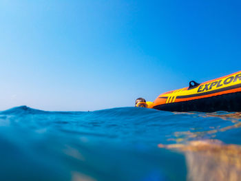 Boy swimming in sea against clear blue sky during sunny day