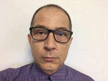 Portrait of young man wearing eyeglasses against white background