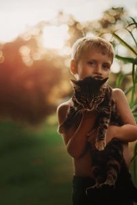 Portrait of boy with cat standing outdoors