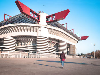 Rear view of woman with umbrella walking against sky