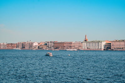 View of buildings by sea against blue sky