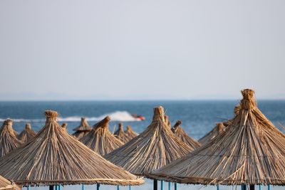 Thatched roofs at beach against clear sky
