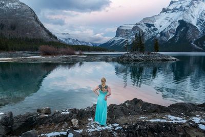 Portrait of young woman standing by lake against mountain