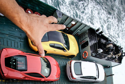 Optical illusion of man reaching for car in boat over sea