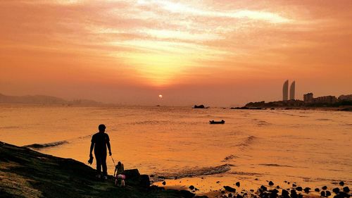 People standing on beach against sky during sunset