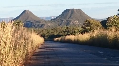 Road by mountains against sky