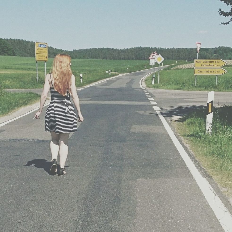 road, rear view, real people, full length, one person, day, the way forward, transportation, walking, casual clothing, leisure activity, women, lifestyles, outdoors, standing, clear sky, young women, blond hair, young adult, nature, sky, adult, people