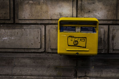 Close-up of yellow mailbox on wall