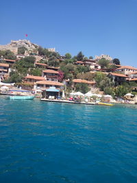 Buildings by sea against blue sky