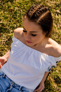 High angle of beautiful woman lying on grassy field