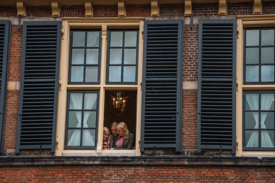 Woman sitting on window of building
