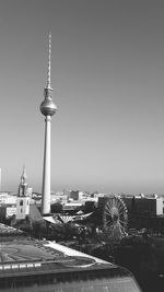 Communications tower in city against clear sky