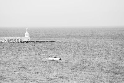 Boat sailing in sea against clear sky