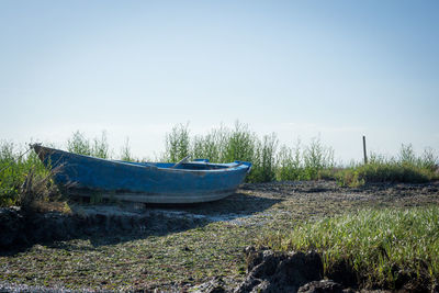 Abandoned boat moored on shore against sky