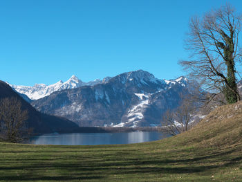 Scenic view of lake by snowcapped mountains against clear sky