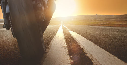 Surface level of road against sunset sky