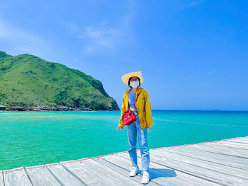 Rear view of woman standing against sea against sky