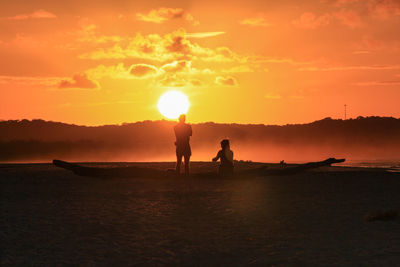 Silhouette people on boat in sea against sky during sunset