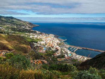 Aerial view of town by sea against sky