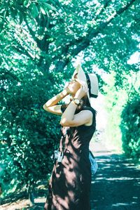 Midsection of woman standing by tree against plants