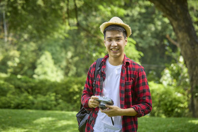 Portrait of smiling young man standing against trees