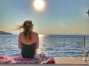 Woman looking at sea against sky during sunset