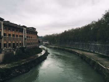 Canal by trees against sky