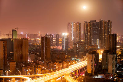 Road and buildings against clear sky in city at dusk