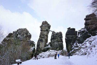 Rear view of man standing on rock against sky