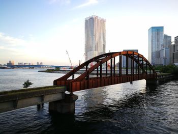 Bridge over river in city against sky