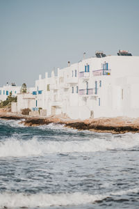 Buildings by sea against clear sky