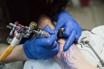 Artist tattooing on hand at studio