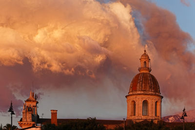 The dome of the basilica of riposto at dawn with the sky darkened by the eruption of etna