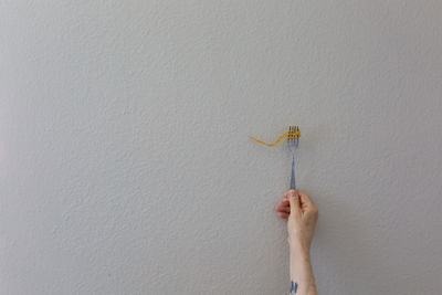 Cropped hand of woman holding gift against wall