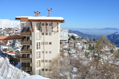 View of building on snow covered mountain against clear sky