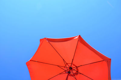 Low angle view of red umbrella against blue sky