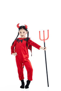 Full length portrait of boy standing against red background